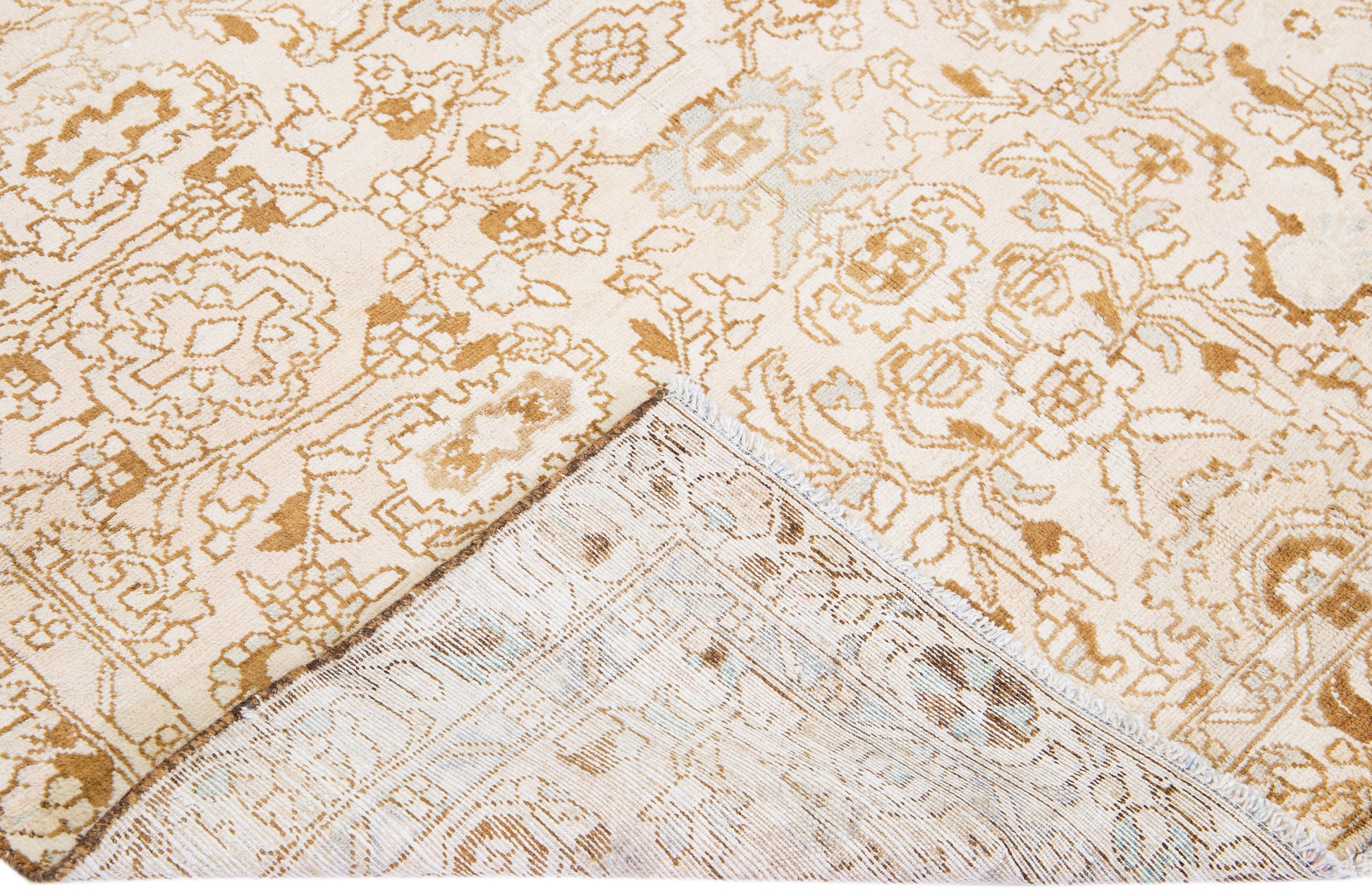 Close up of backside of beige wool rug with floral designs and interwoven patterns