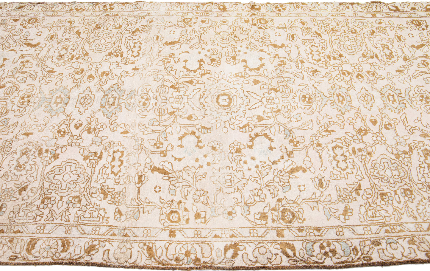 Close up of beige wool rug with floral designs and interwoven patterns