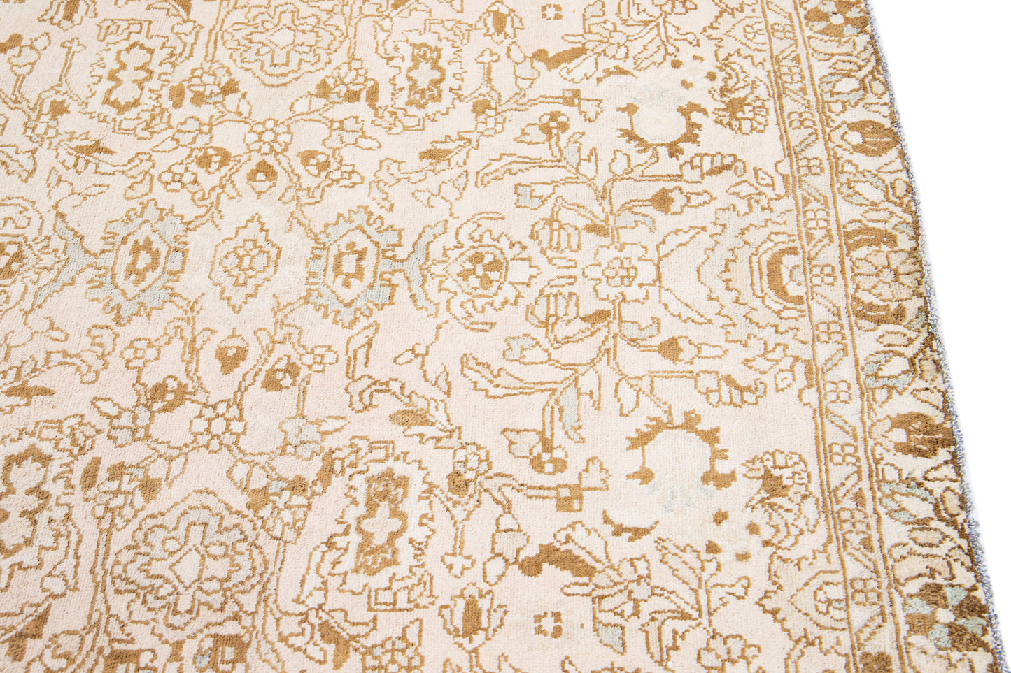 Close up of beige wool rug with floral designs and interwoven patterns