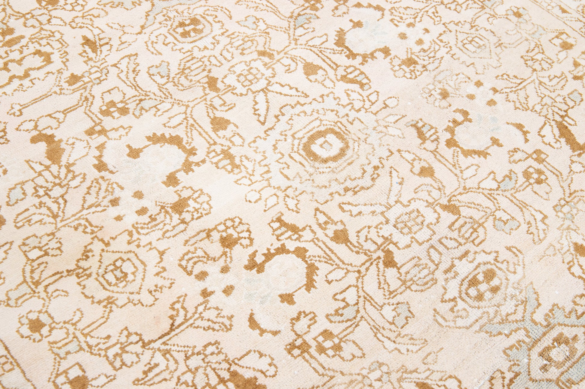 Close up of beige wool rug with floral designs and interwoven patterns